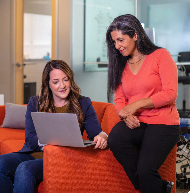 The digital marketing agency's manager presents design options on her computer to her client.